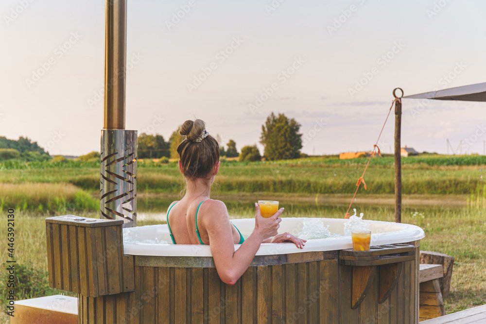 Woman enjoy outside of  japanese hot tub gardens in romantic nature environment. Idyllic bathtub in sunset